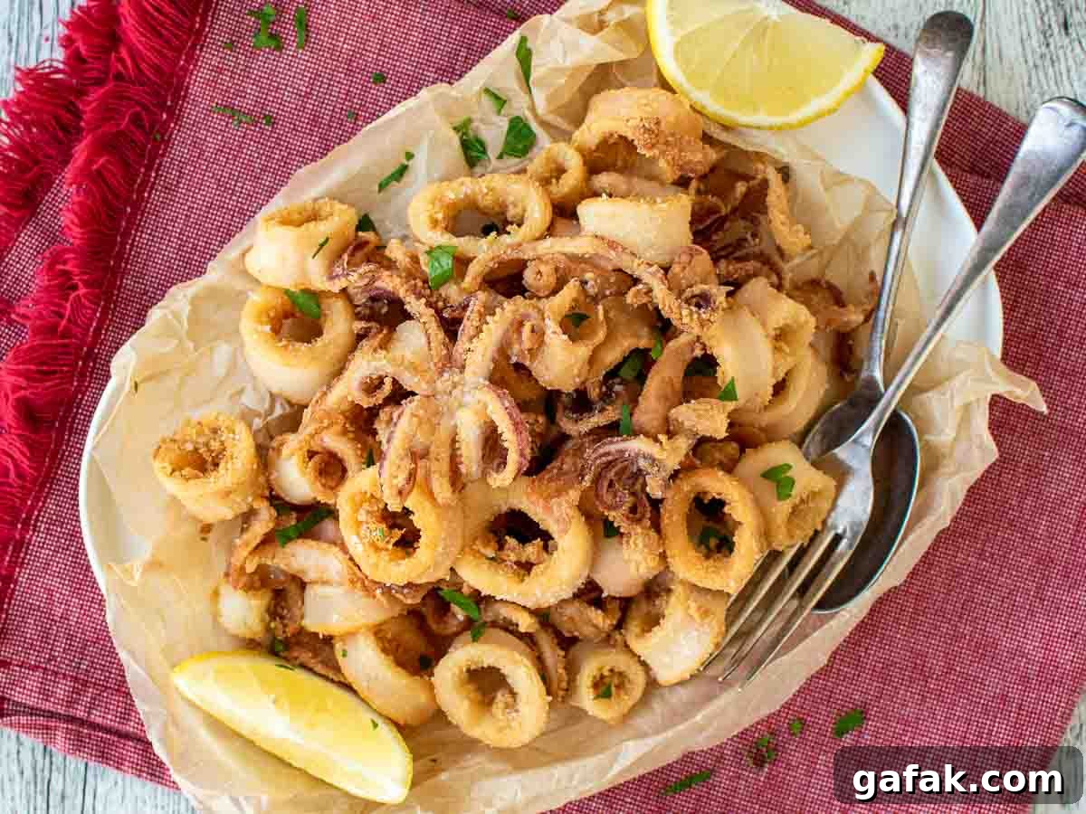 Platter of golden brown calamari rings and tentacles with lemon wedges on the side.