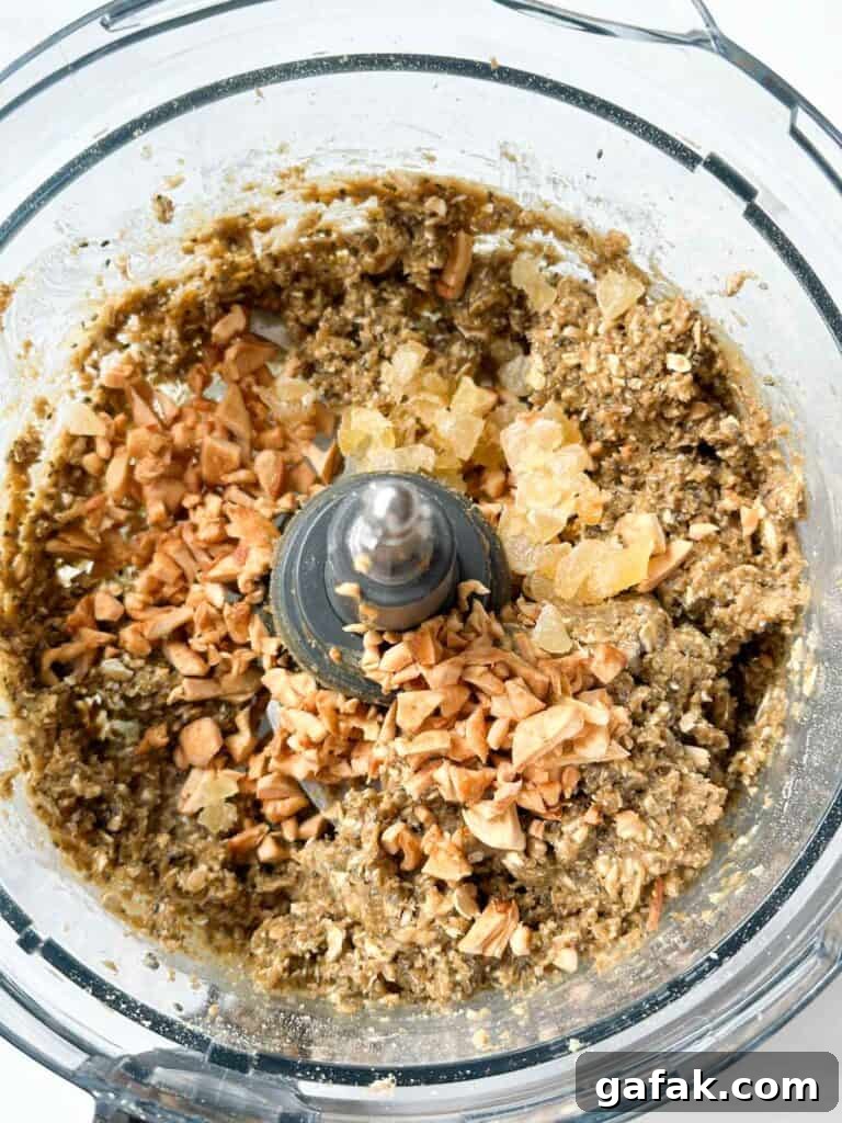 Adding in ginger and dried apples to the protein ball dough mix.