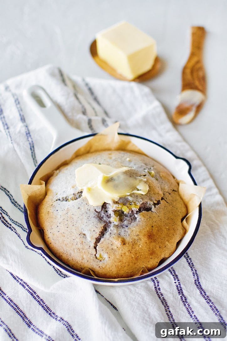 Blue Cornbread in a skillet with butter spread on top.