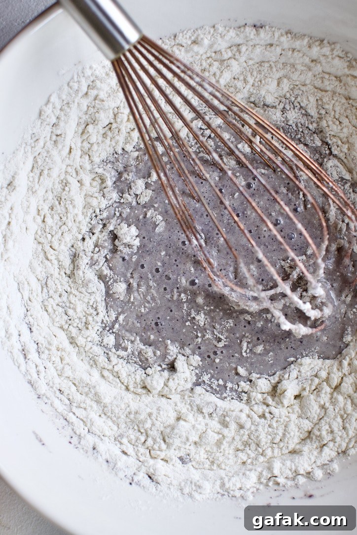 Dry ingredients for cornbread being whisked into the wet ingredients.