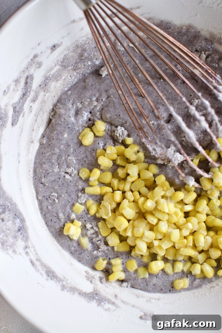 Mixing the frozen corn into the cornbread batter.