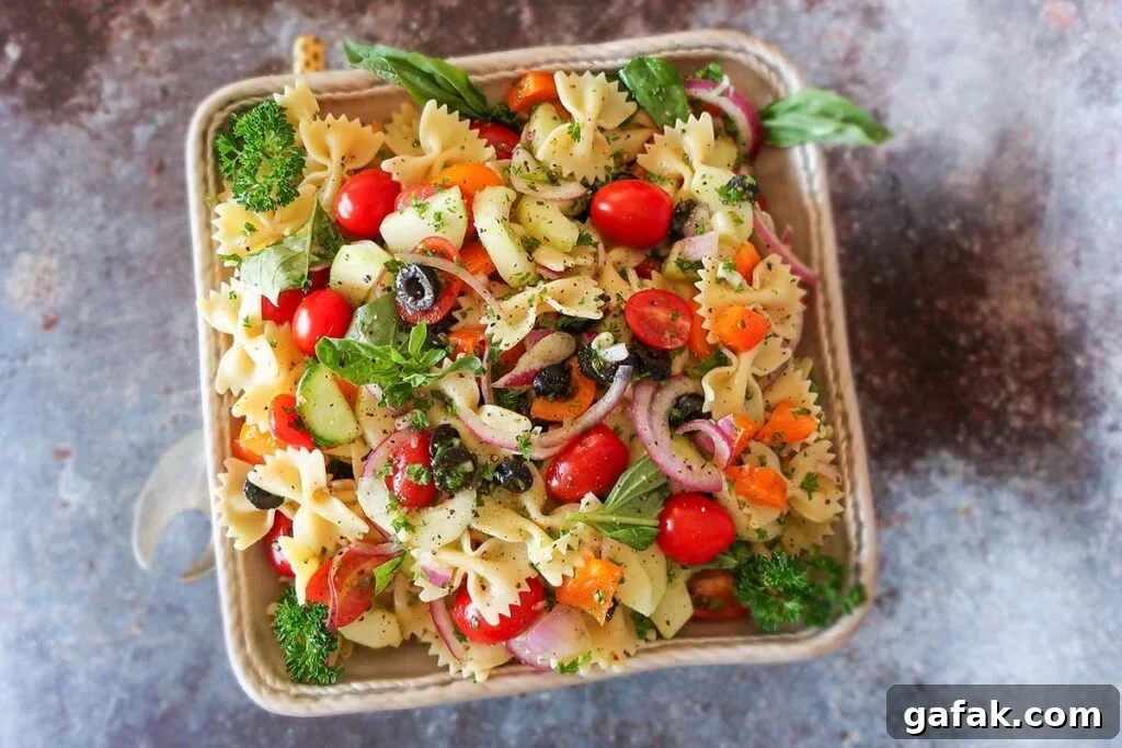 summer pasta salad with olives, tomatoes, onions and herbs in a bowl