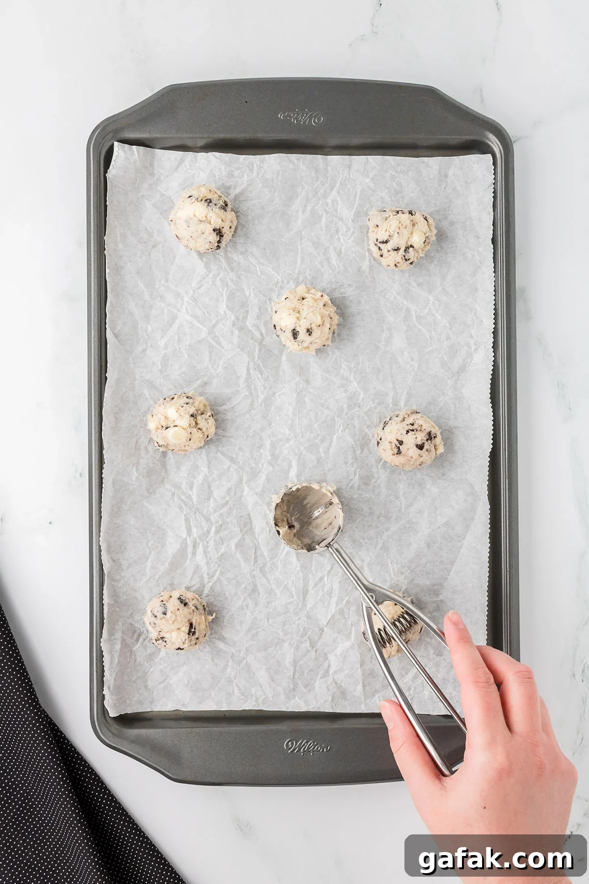 Cookie dough balls placed on a parchment paper lined baking sheet.