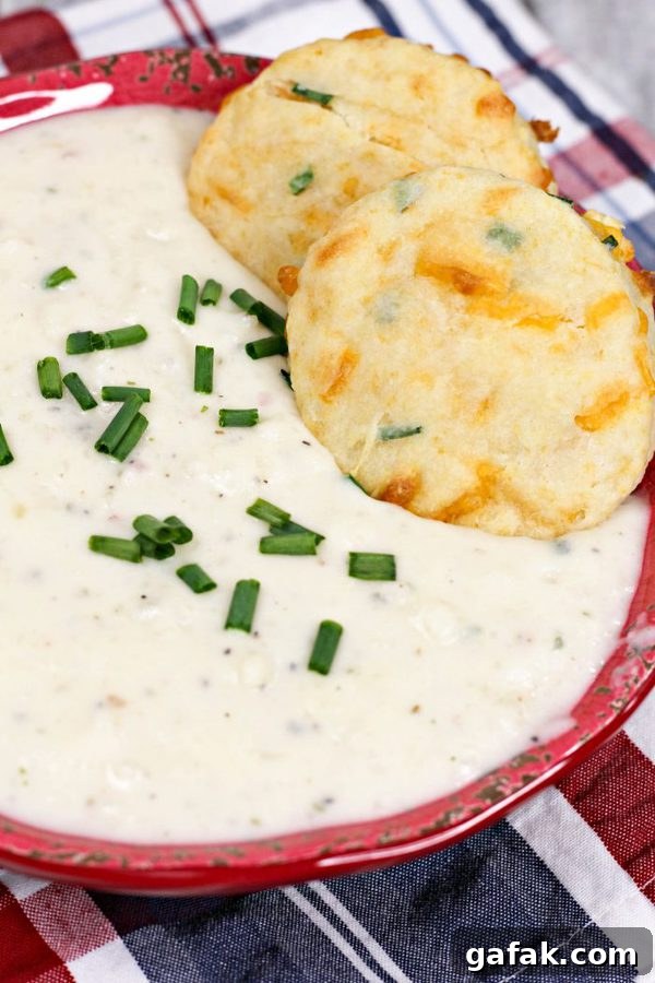 a bowl of potato soup topped with chives and homemade cheddar biscuits.