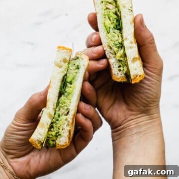 avocado and tuna salad in a sandwich being held