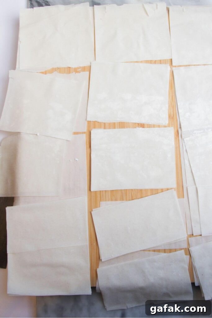 Square pieces of filo pastry on a wooden board.