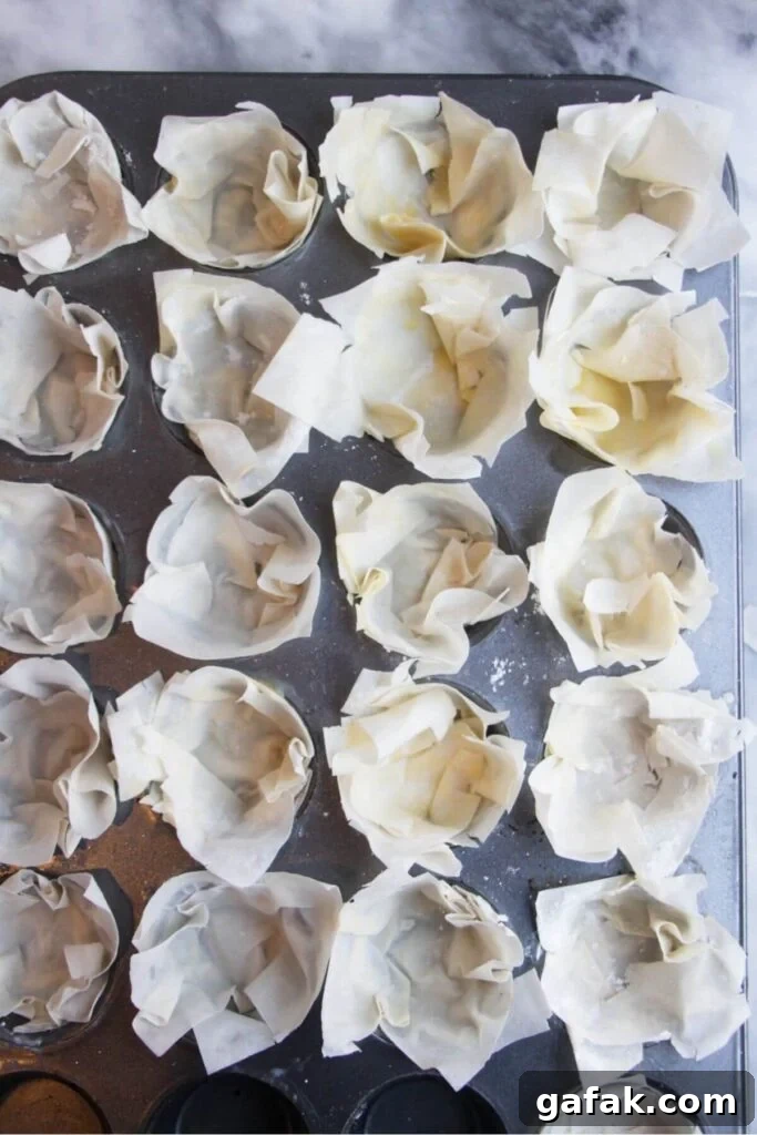 Squares of filo pastry pressed into s mini muffin tin.
