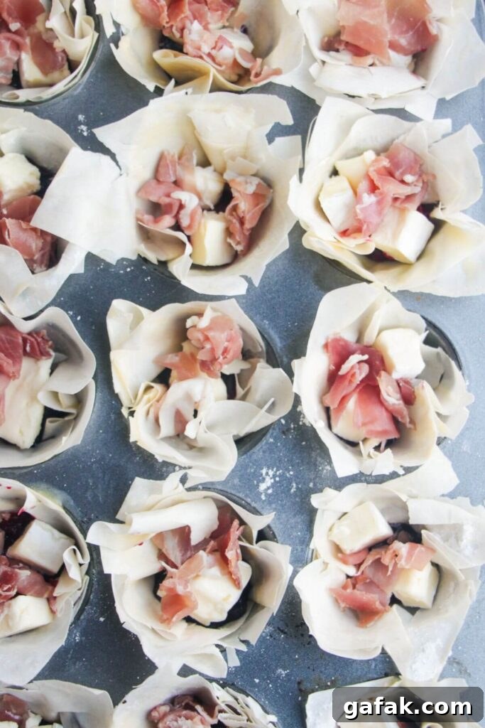 Brie, prosciutto and cranberry sauce in filo pastry cups.