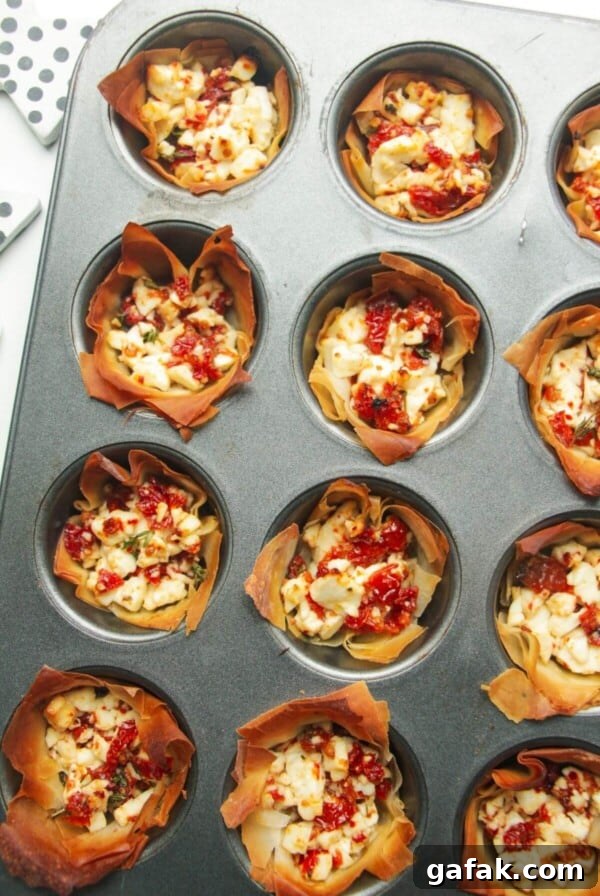 Close up of baked sundried tomato feta cups in a mini muffin tin.
