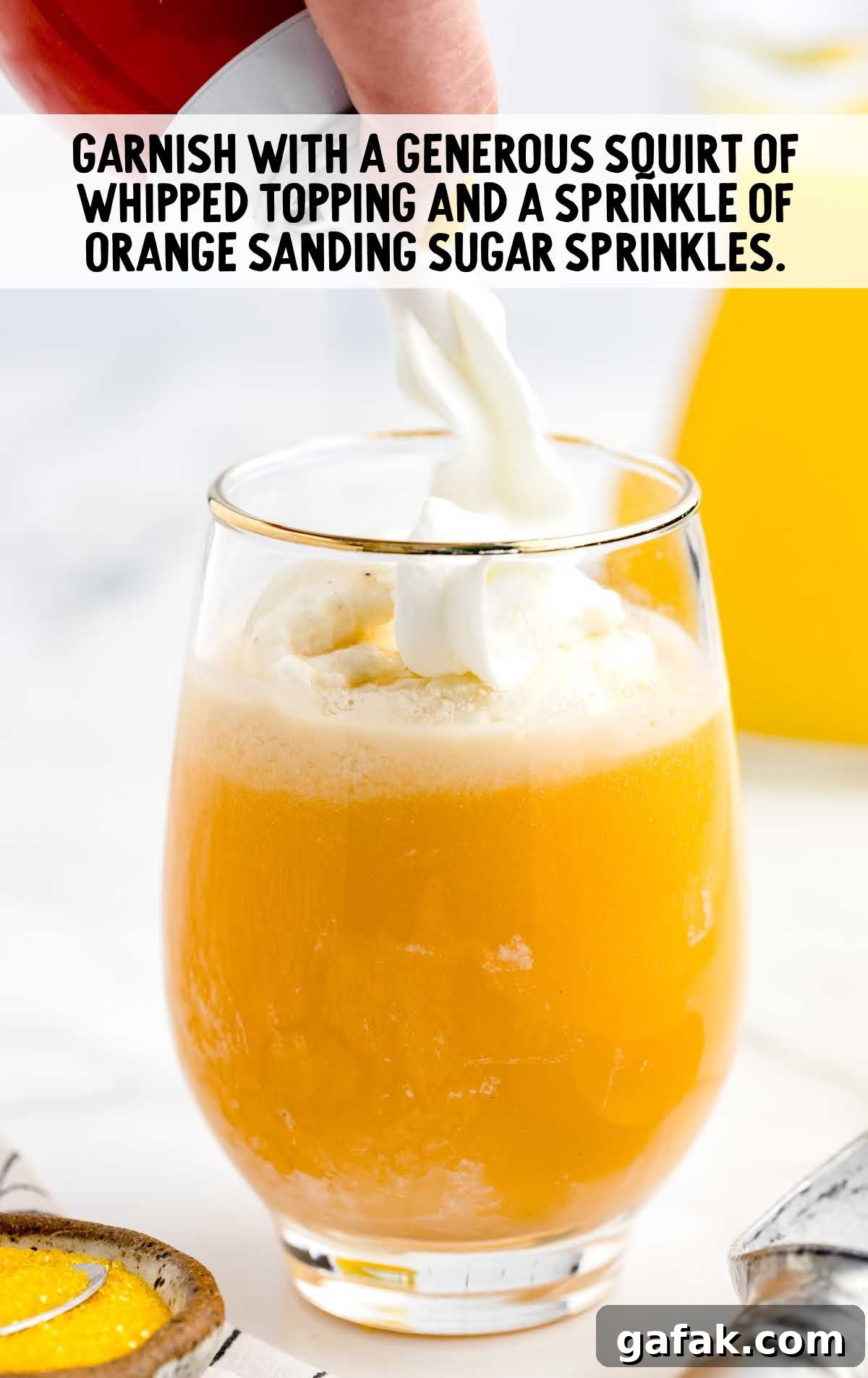 whipped topping garnished on top of the cocktail and orange sanding sugar sprinkled in a glass