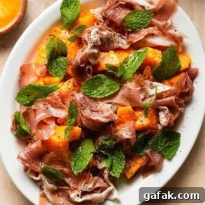 Plate of melon salad with prosciutto, fresh mint, and cracked black pepper.