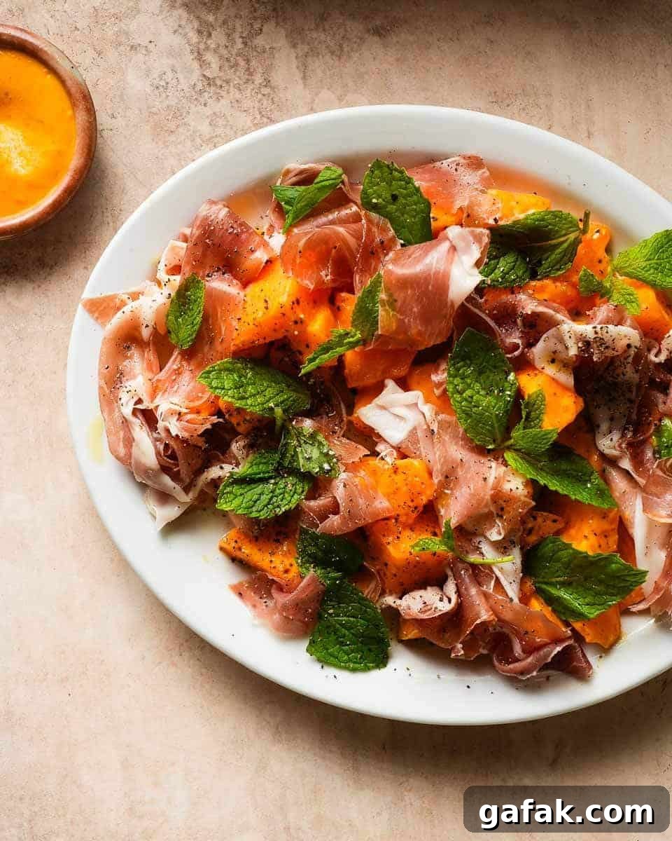 a platter of melon prosciutto salad beside a sauce of accompanying vinaigrette