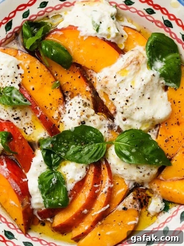 Fresh peach and burrata salad with basil, in a decorative bowl.