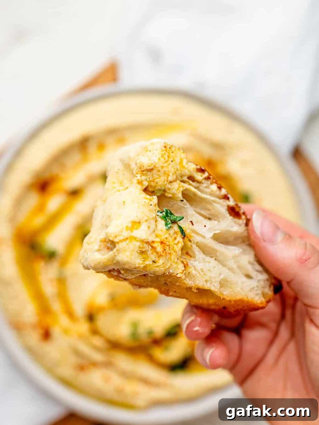 Creamy Cottage Cheese Hummus with a drizzle of olive oil spread out on a plate.