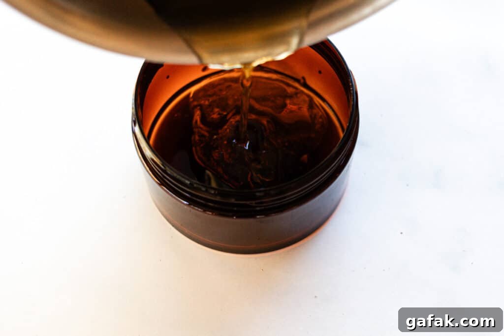 Pouring the melted foot mask ingredients out of the saucepan into the container.