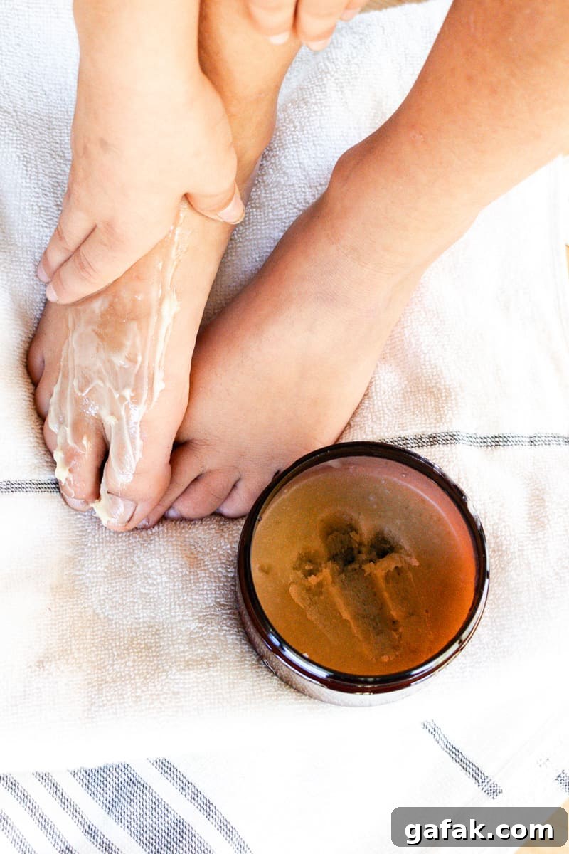Generously applying the foot mask while resting my feet on a towel to prevent messes.