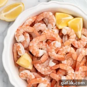 How to Poach Shrimp Perfectly Every Time 15 overhead of poached shrimp in a white fluted pie plate with lemon wedges