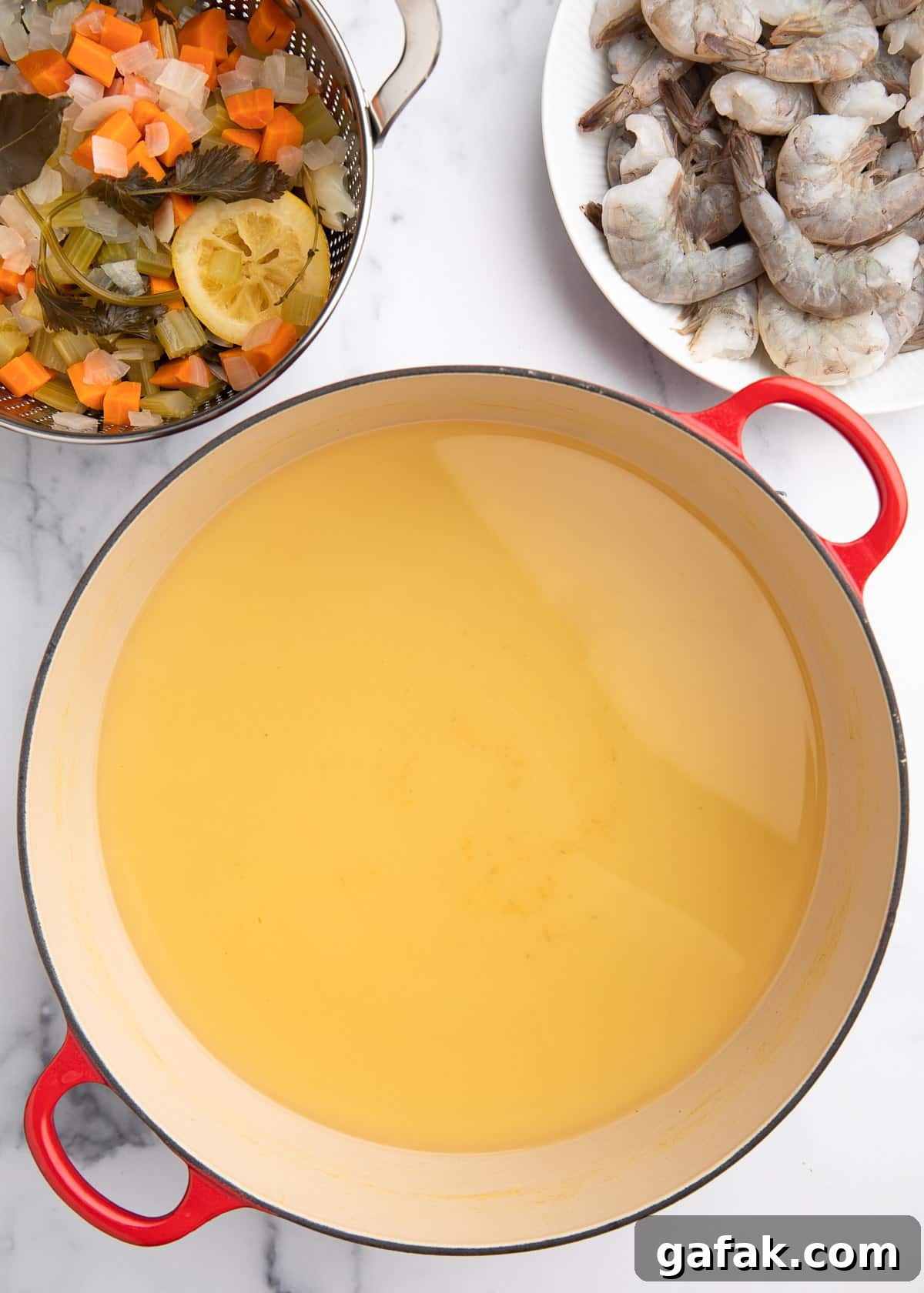 How to Poach Shrimp Perfectly Every Time 7 strained court bouillon in a Dutch oven with raw shrimp nearby