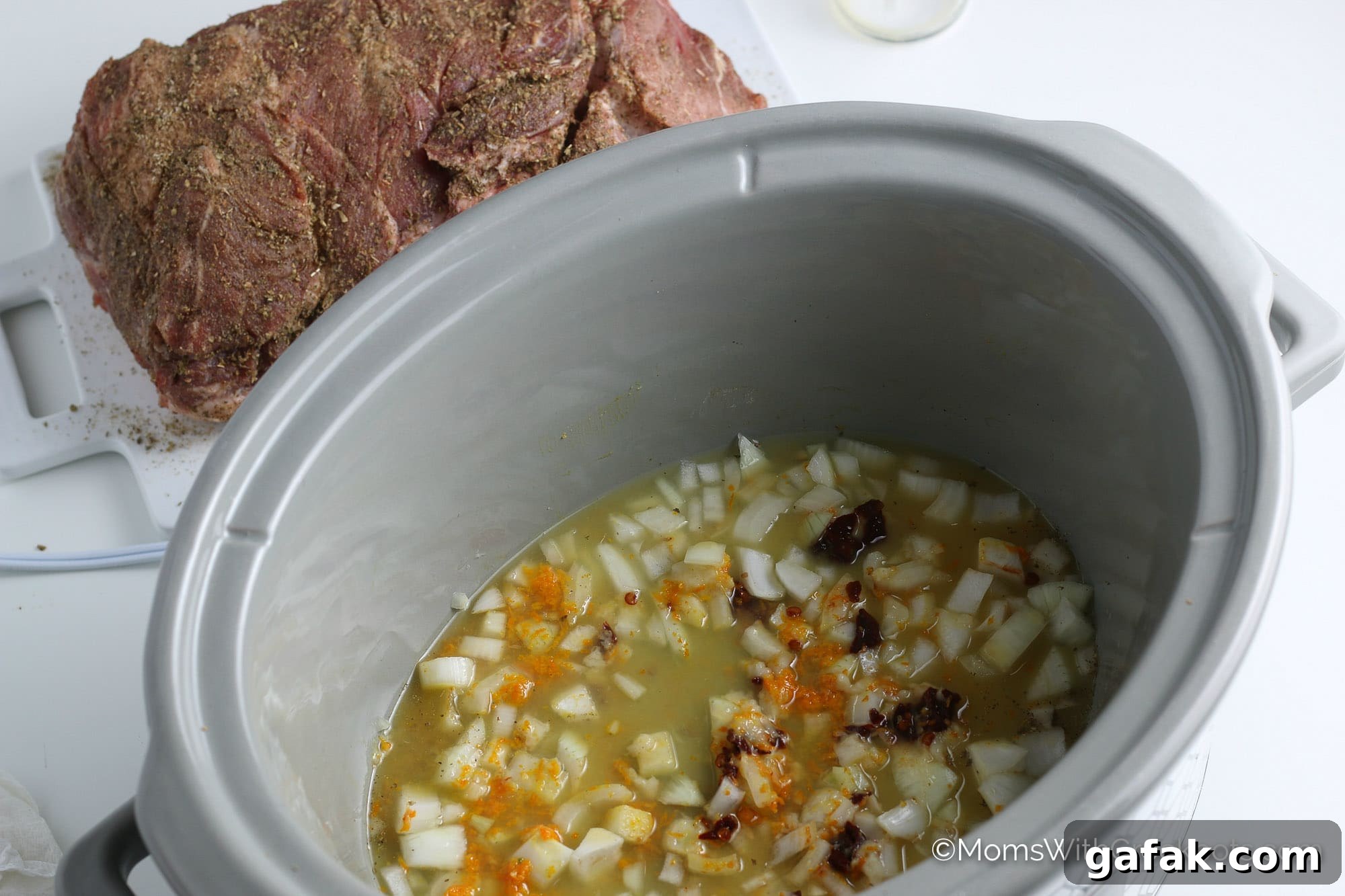 mojo in slow cooker with pork roast behind.