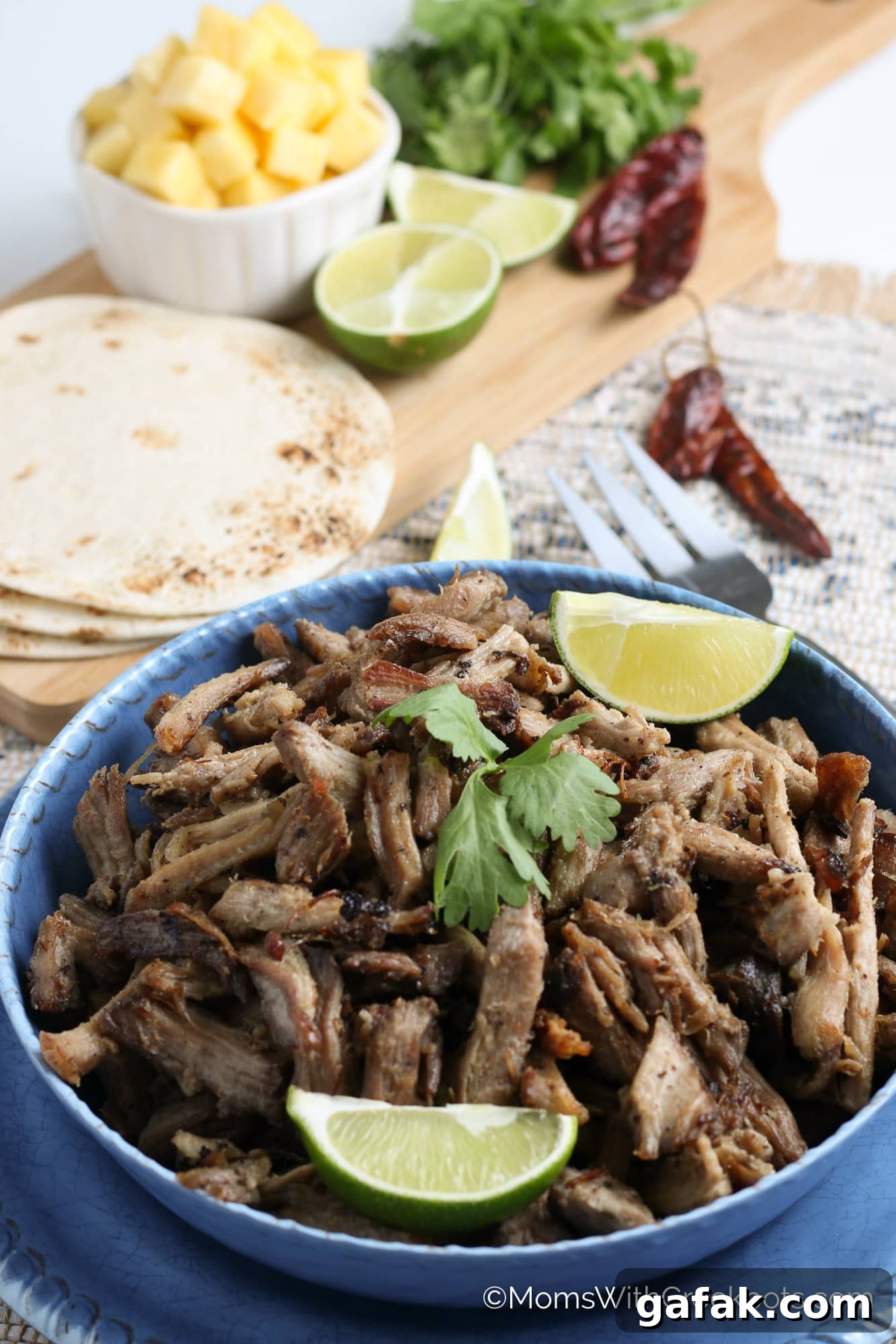 Crispy Slow Cooker Carnitas in bowl with tortillas