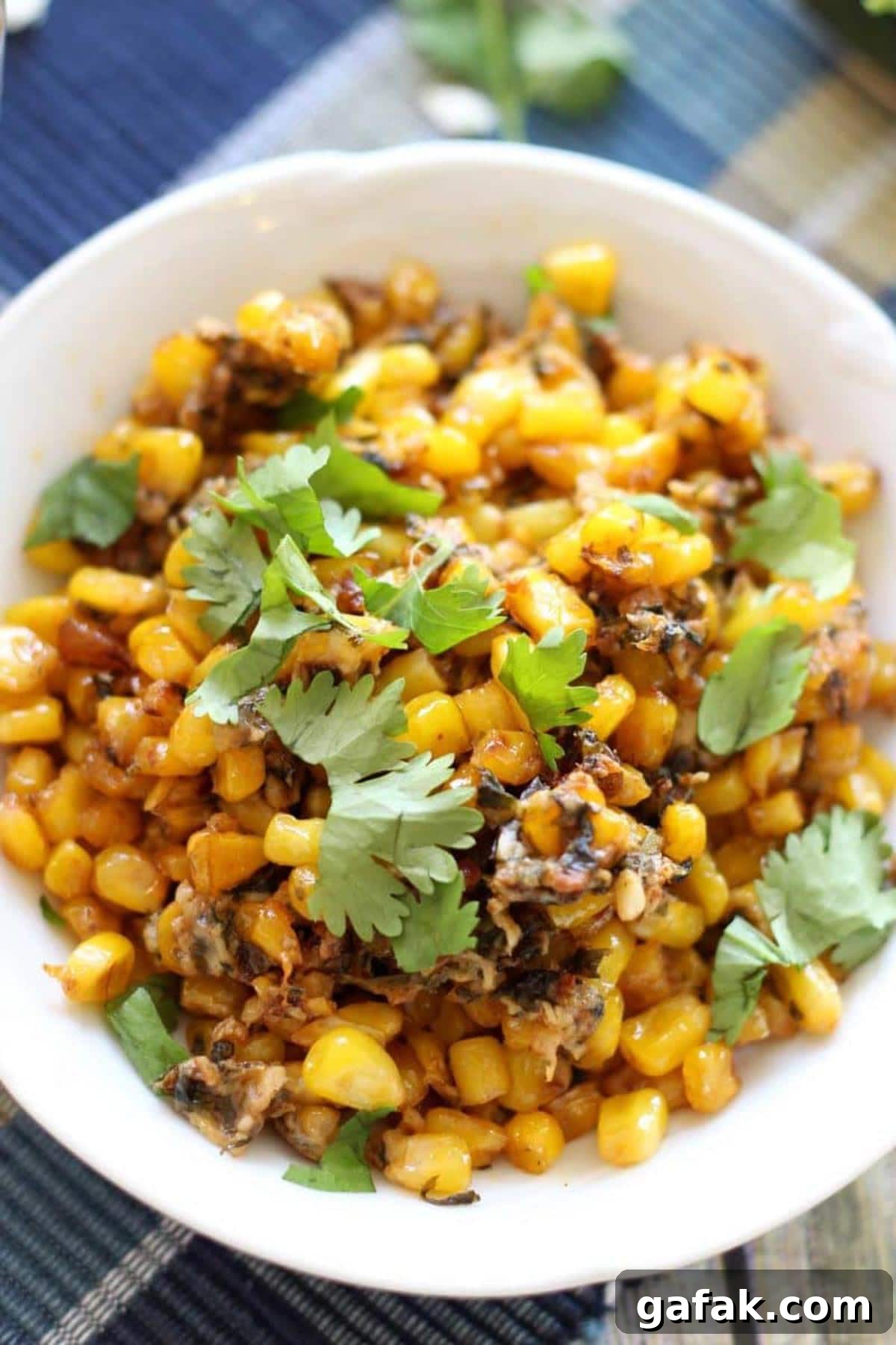 Authentic Mexican Street Corn (Elote) Recipe — Grilled & Creamy 2 White bowl containing Mexican Street Corn topped with cilantro.