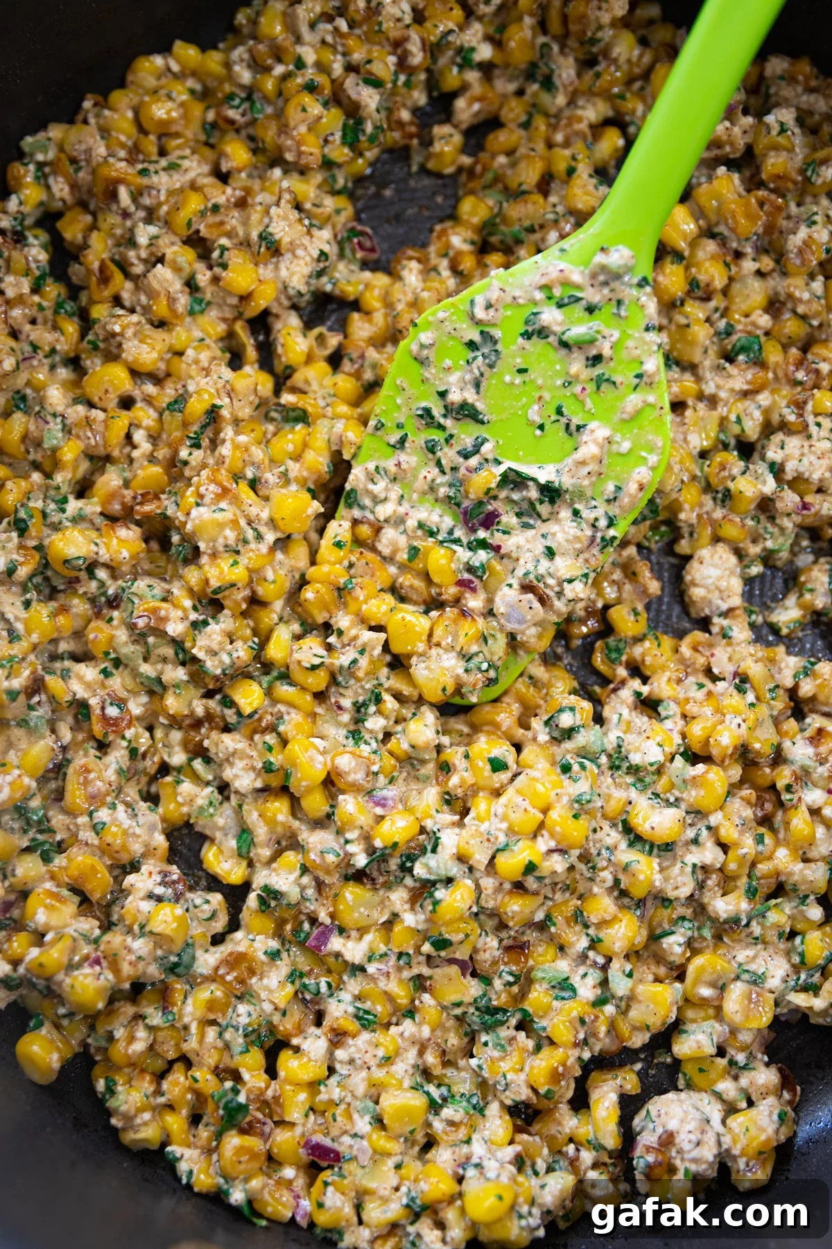 Authentic Mexican Street Corn (Elote) Recipe — Grilled & Creamy 7 Mexican corn in a skillet being served with a spatula.
