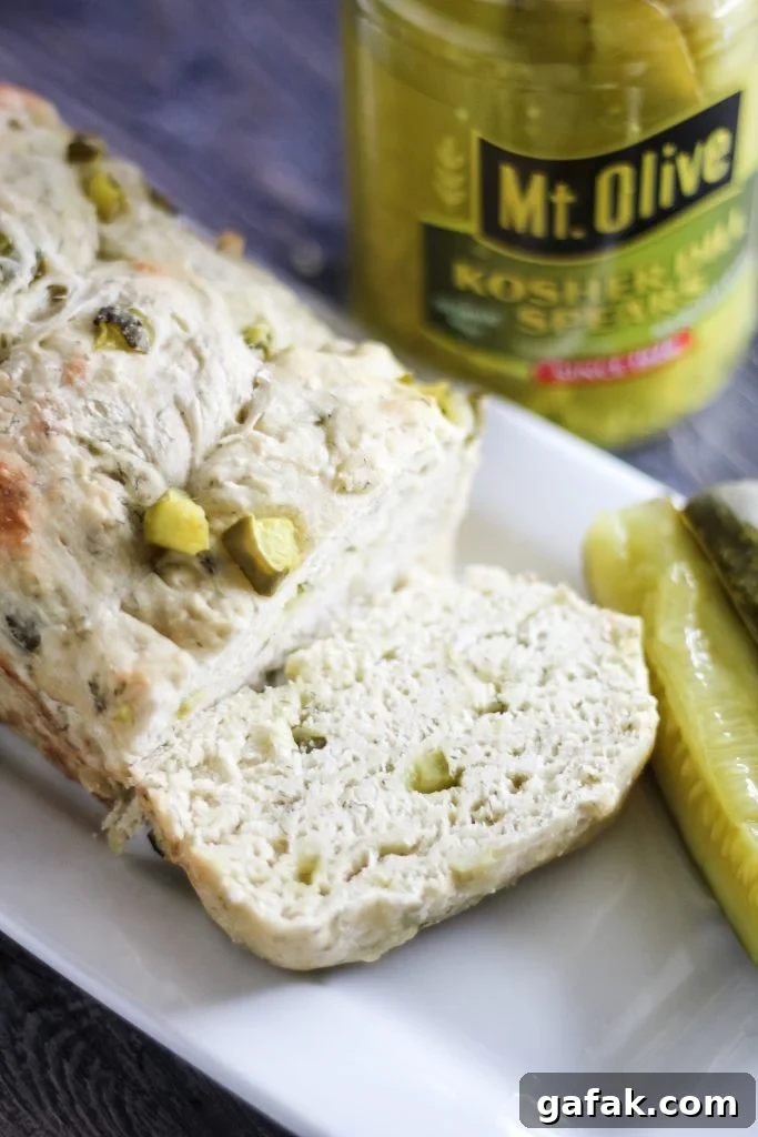 dill pickle bread shown sliced on a white serving platter with pickle spears on the side