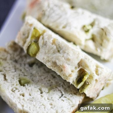 dill pickle bread shown sliced on a white serving platter with pickle spears on the side
