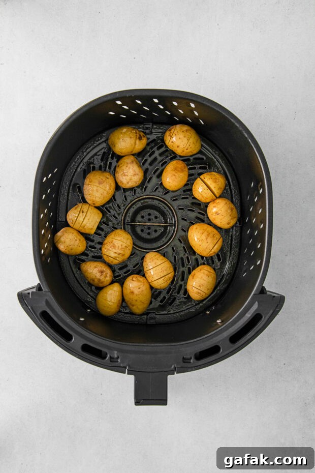 Uncooked potatoes in an air fryer basket. 