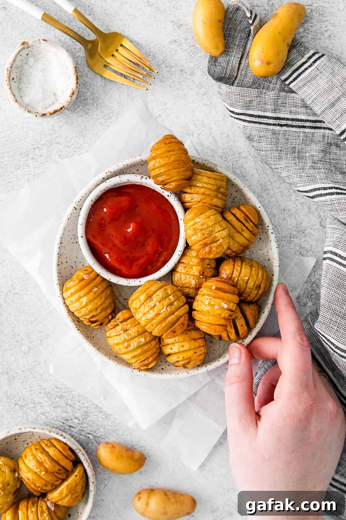 Air Fryer Hasselback Potatoes on a plate with ketchup and kosher salt. 