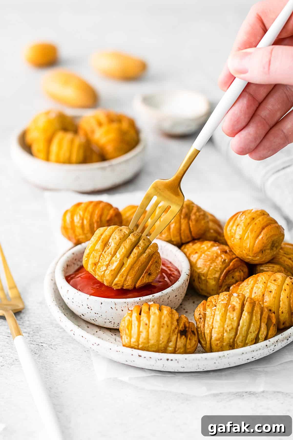 Air Fryer Hasselback Potatoes on a plate with a fork picking it up. 