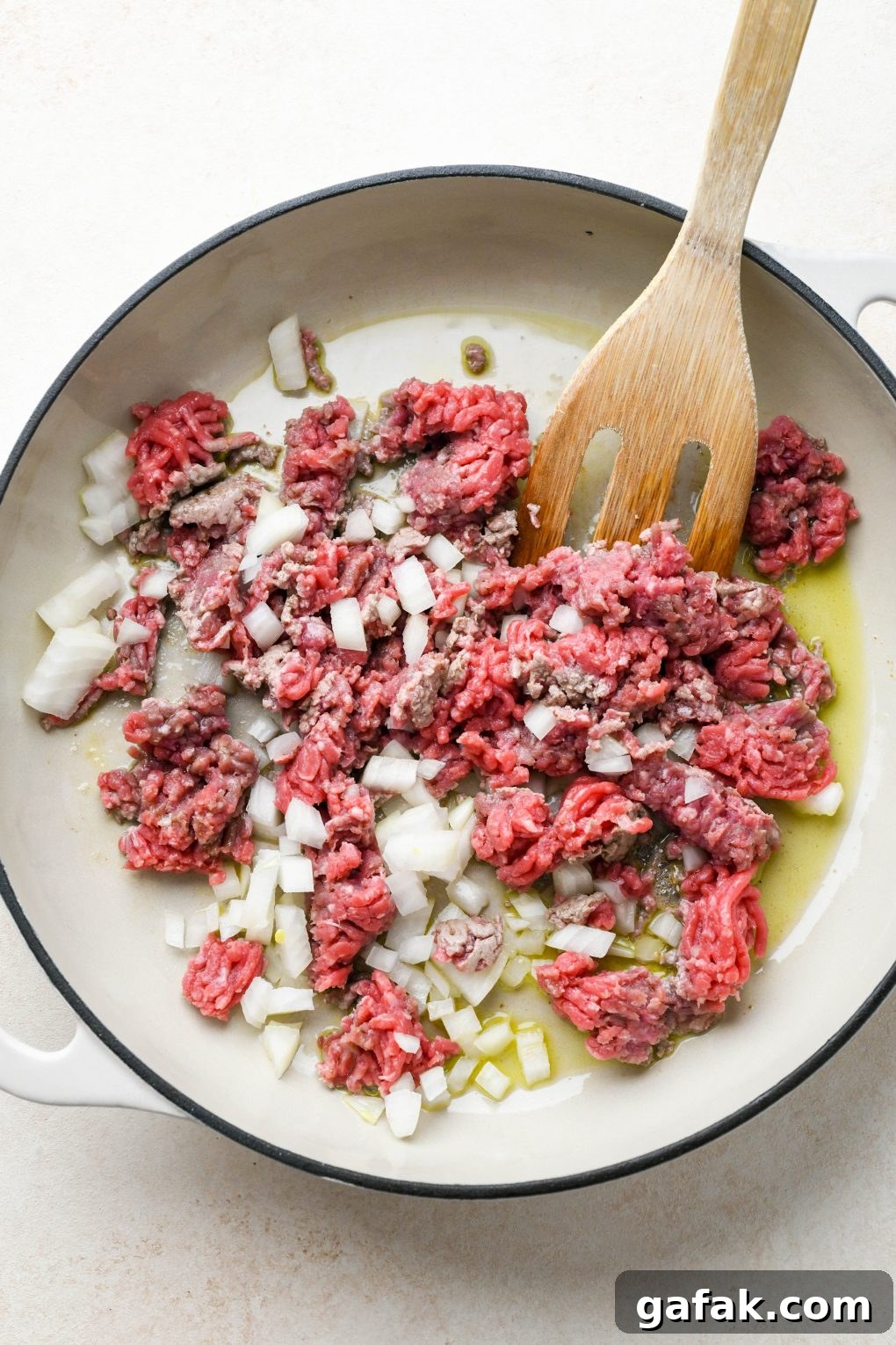 How to make Dairy Free Queso Fundido with Ground Beef: Raw ground beef with diced onion in skillet. 