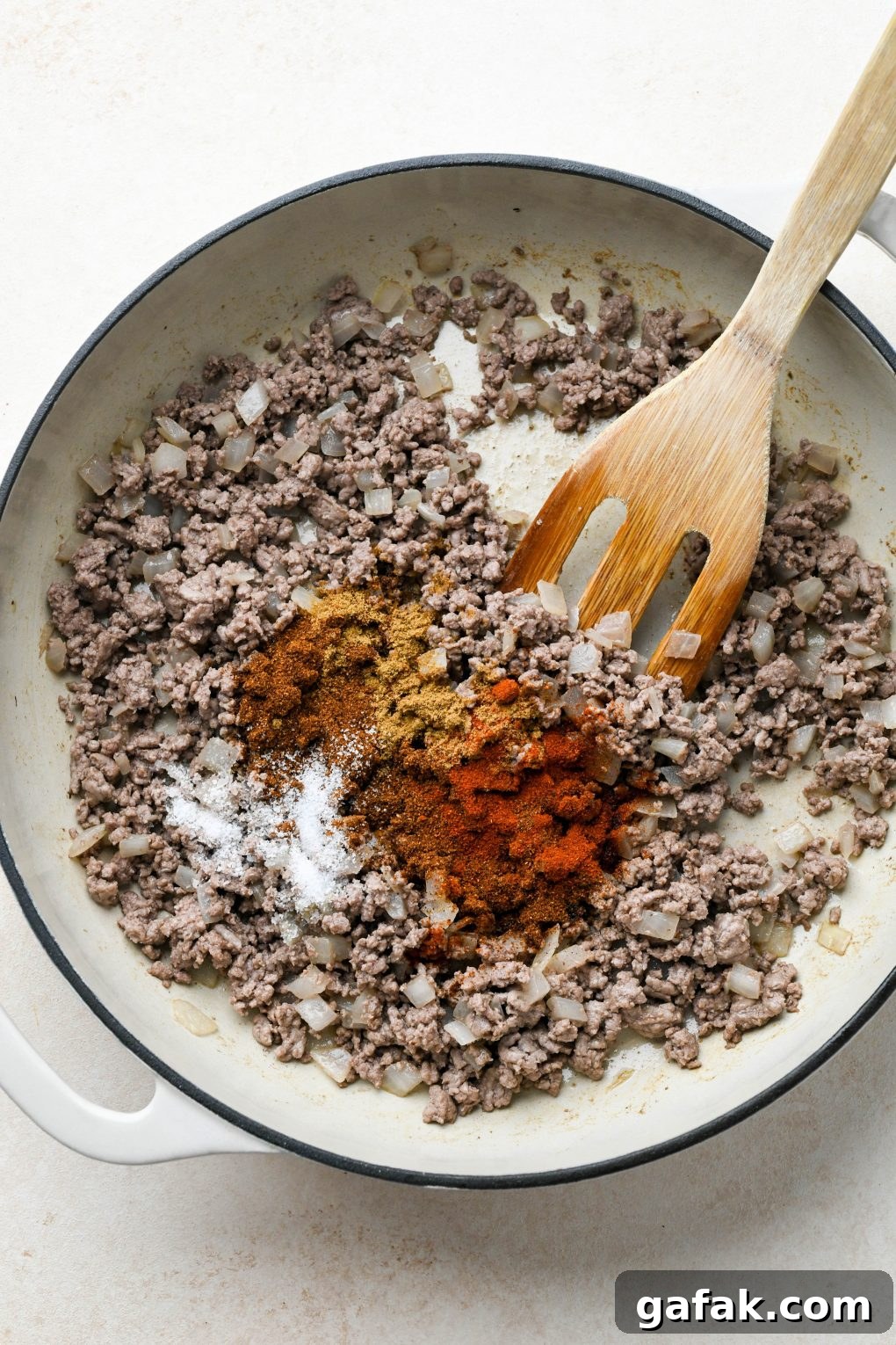 How to make Dairy Free Queso Fundido with Ground Beef: Cooked ground beef and onion in skillet with spices on top.