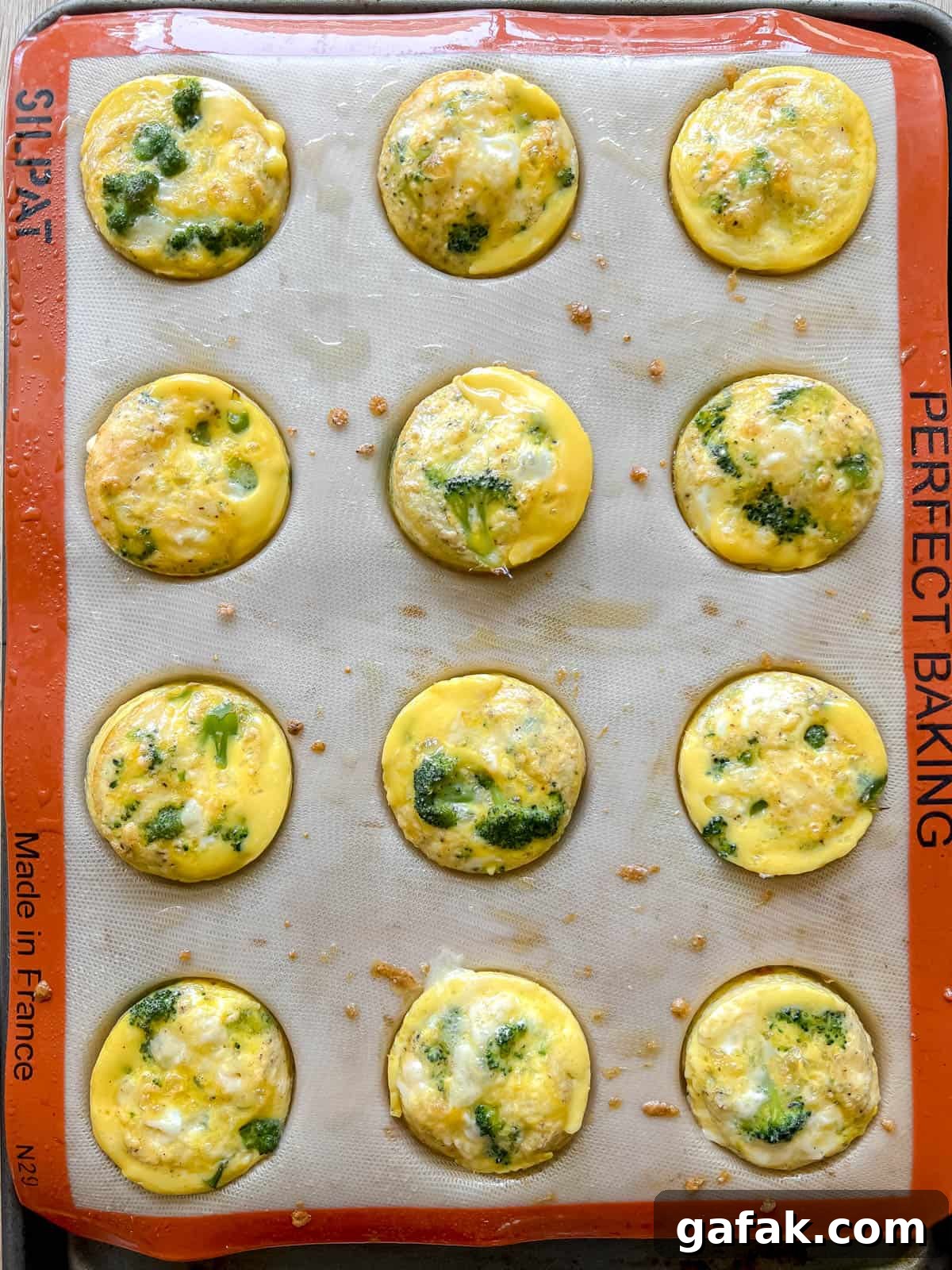 Freshly baked broccoli cheddar egg muffins in silicone tins.