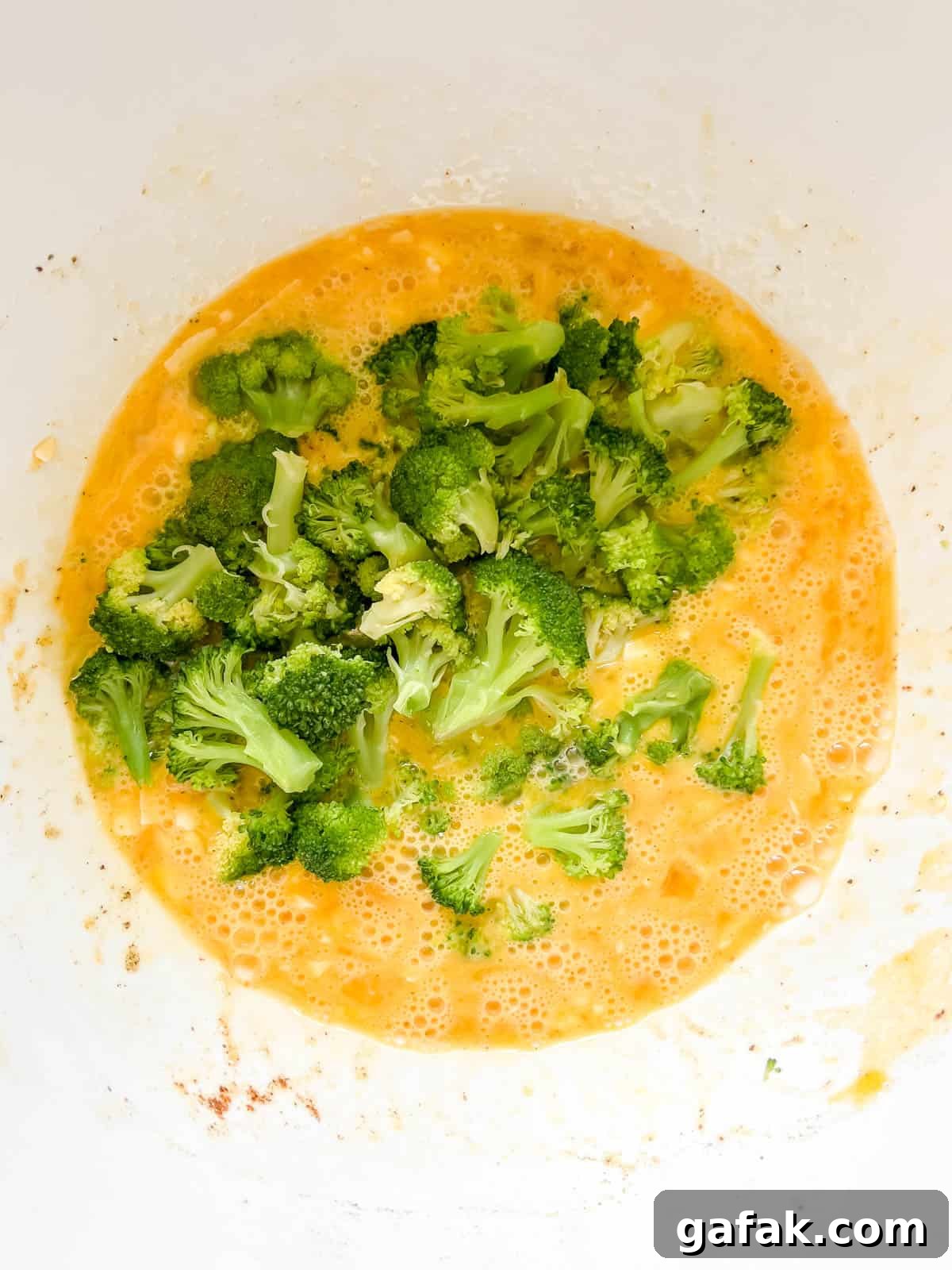 Broccoli added to egg muffin mixture.