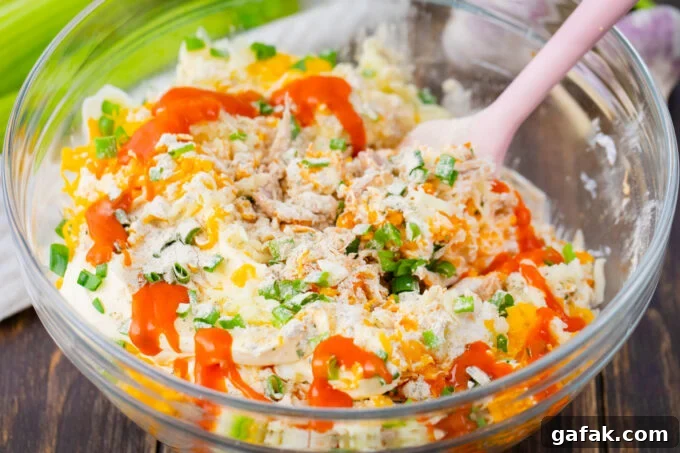 Stirring Buffalo crack chicken dip ingredients in a bowl.