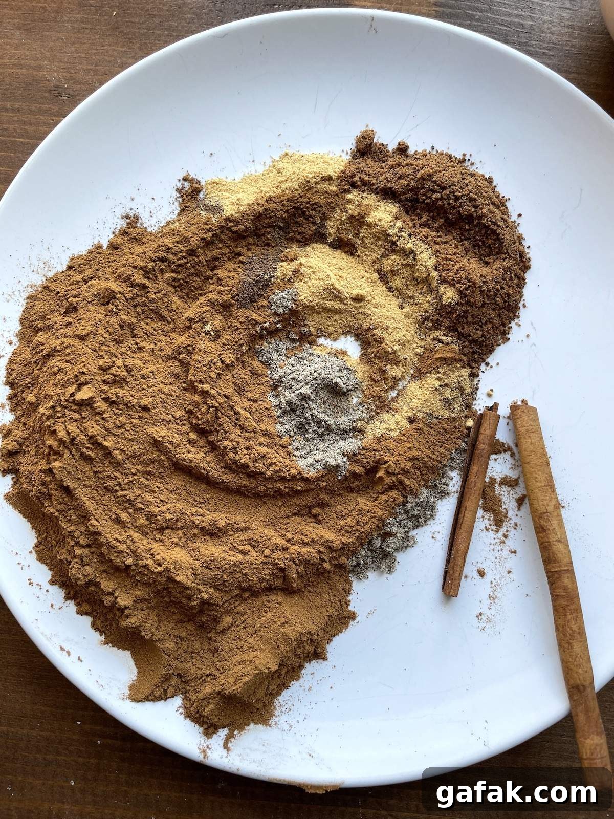 The ingredients in apple pie spice mix on a plate swirled together on a white plate.