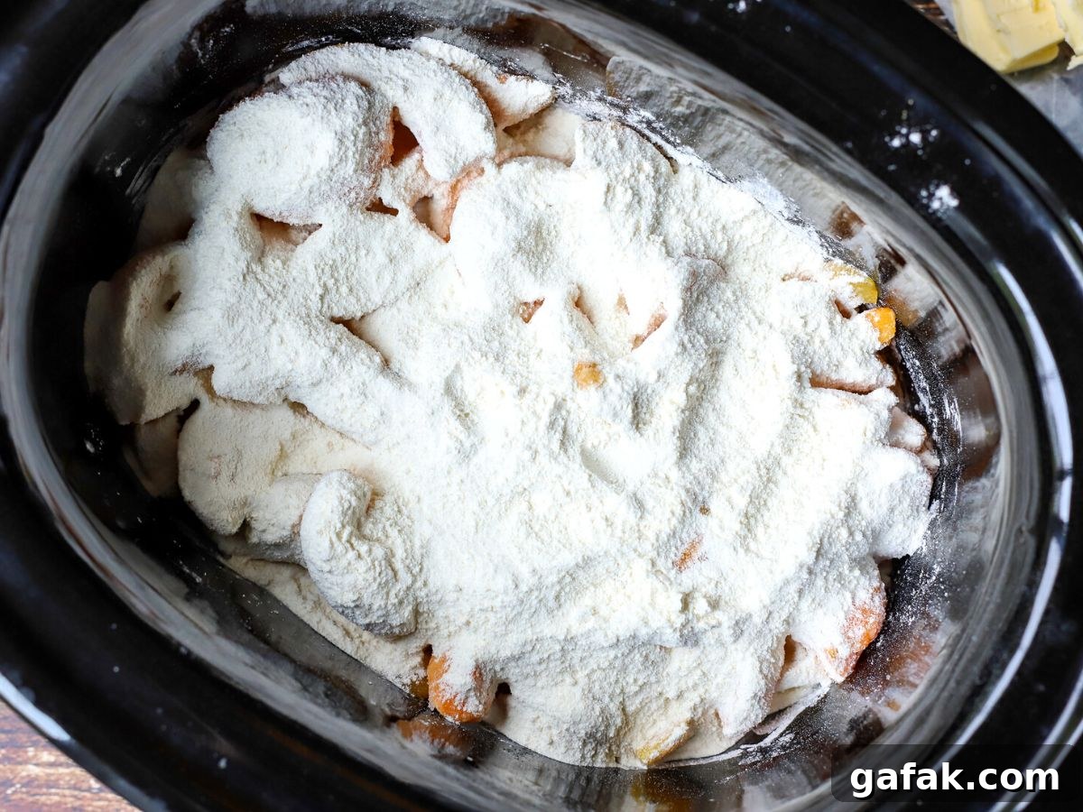 peaches in a crock pot with flour and sugar on top.