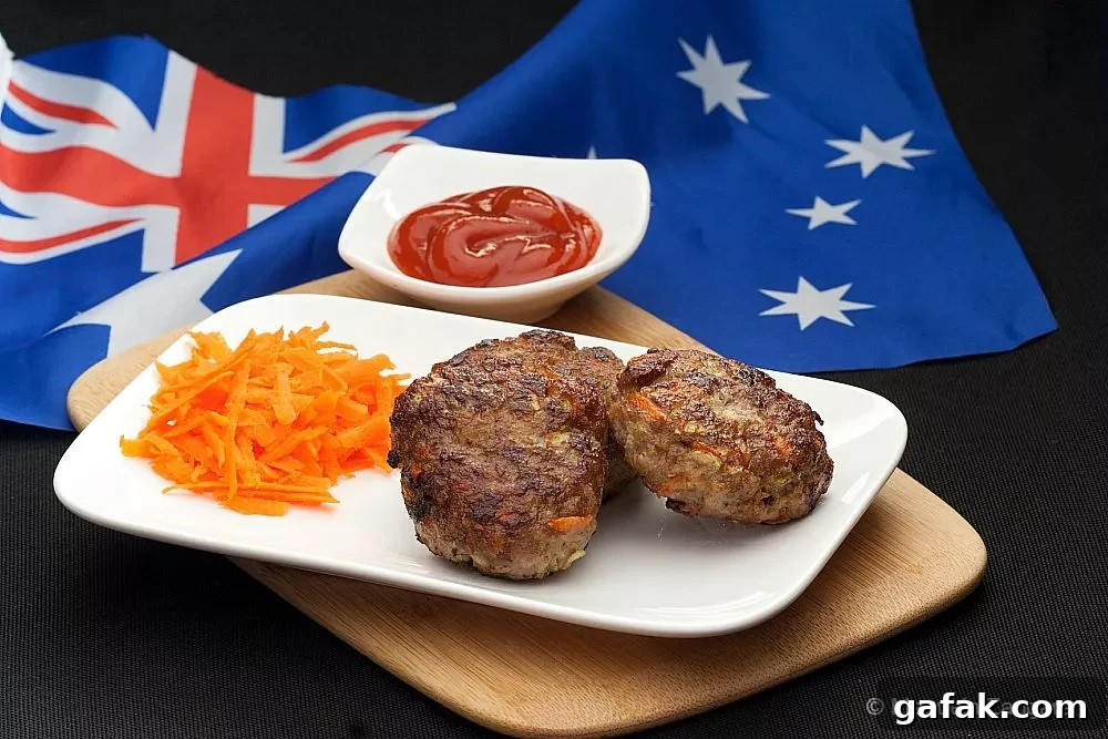 Rissoles: Crispy Filled Patties Recipe Guide 2 Juicy beef rissoles on a white plate with grated carrot and tomato sauce, served on a wooden board.