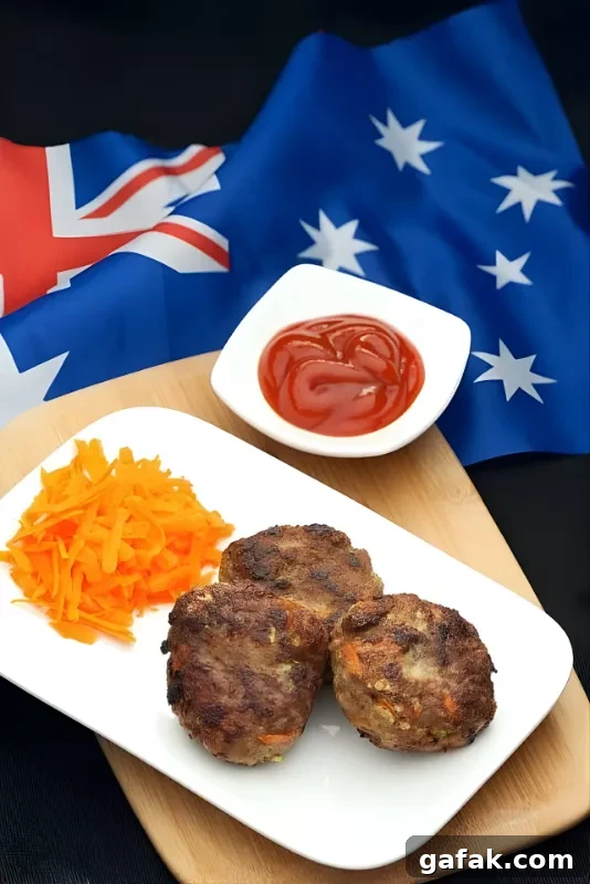 Rissoles: Crispy Filled Patties Recipe Guide 3 Cooked Australian rissoles on a white plate with grated carrot and tomato sauce, placed over an Australian flag.