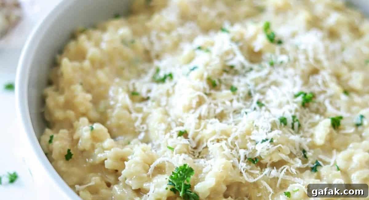 Overhead image of creamy garlic parmesan risotto with garnish in white bowl. 