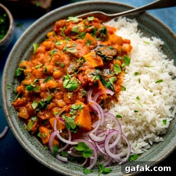 chickpea and sweet potato curry in a bowl with rice and red onion