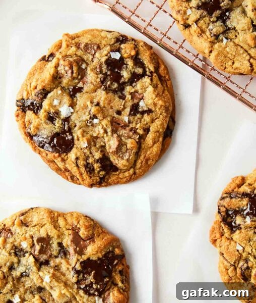 Several bakery style chocolate chip cookies cooling on a rack.