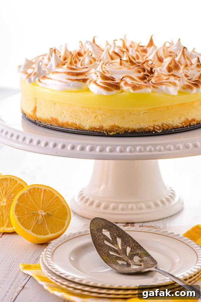 A low carb lemon cheesecake on a cake tray, with sliced lemons on the table nearby.