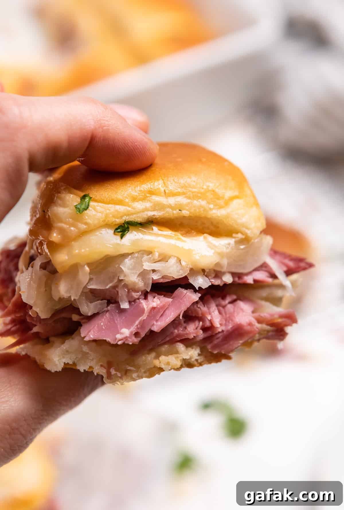 Classic Reuben Sliders with Melted Swiss and Tangy Thousand Island 11 Reuben slider held up to show close up of sandwich.