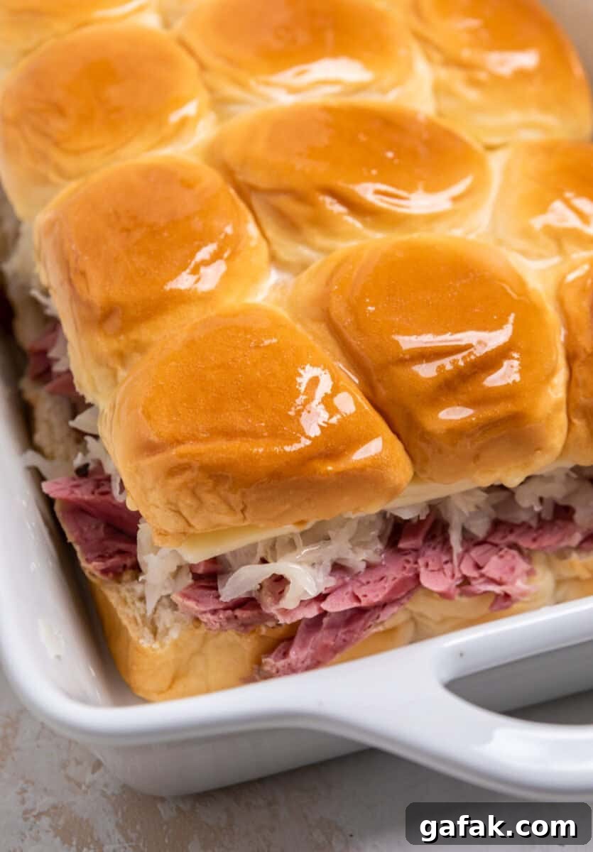 Classic Reuben Sliders with Melted Swiss and Tangy Thousand Island 9 Buttered tops of Hawaiian rolls with corned beef, sauerkraut, swiss cheese in baking pan.