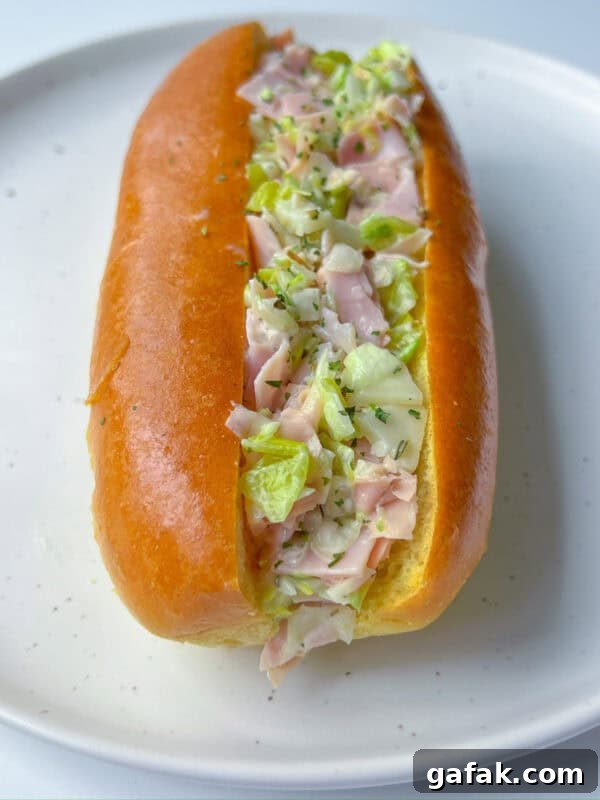 A soft bun filled with chopped ham, lettuce, and mayonnaise, served on a white plate—this Italian Chopped Sandwich brings classic flavors together in every bite.