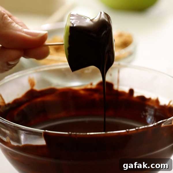 Dipping the apple bite in the melted chocolate.