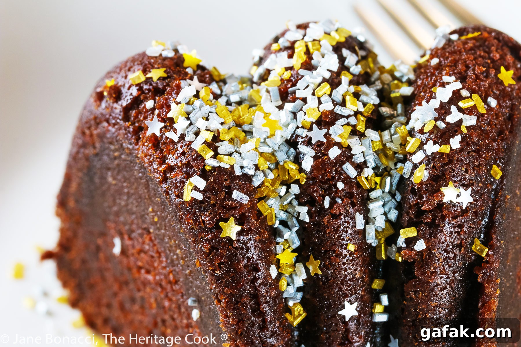 close up of fancy sprinkles (gold and silver stars and sprinkles) on top of slice of cake