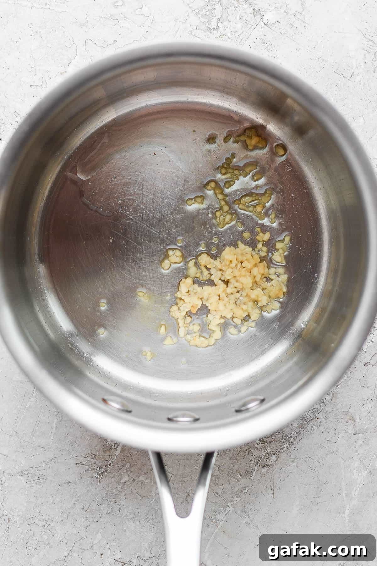 A medium sauce pan with oil and minced garlic in the bottom.